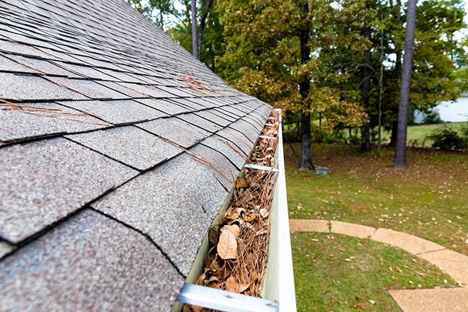 a person on a roof clearing out a gutter